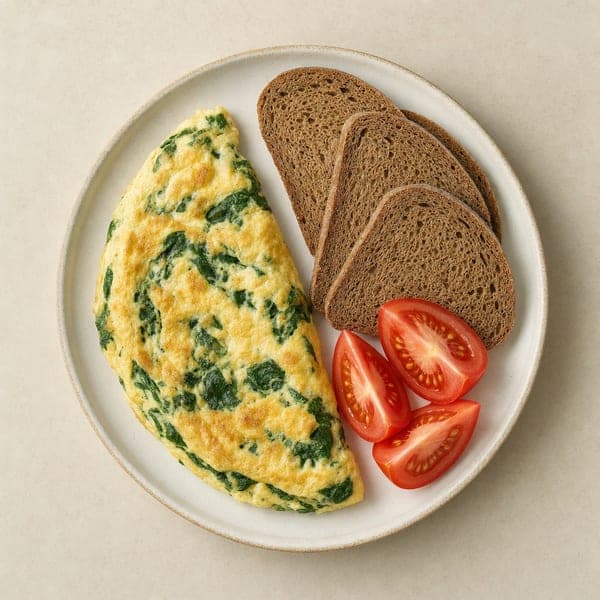 Omlet ze szpinakiem serwowany z chlebem i pomidorem